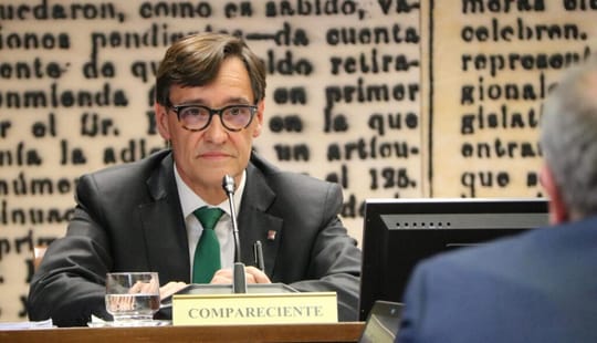 Salvador Illa speaking at a podium with a Catalan flag in the background.