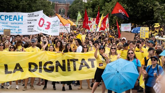 Protesters with banners blocking Avinguda Diagonal in Barcelona, with buses and cars visible in the background.