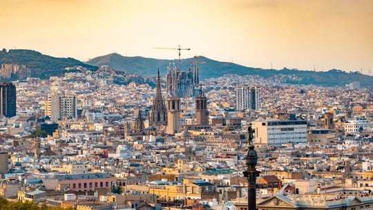 A diverse group of people walking past a historic church and modern buildings in a bustling Barcelona street, representing re