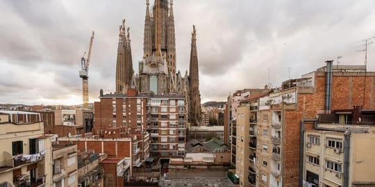 The unfinished Glory Façade of Sagrada Família basilica with surrounding residential buildings in Barcelona.