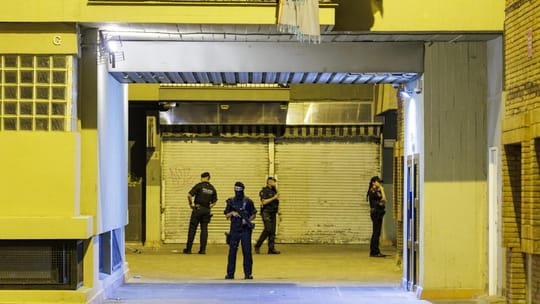 Police tape and officers investigating a crime scene on a city street in Barcelona at night.