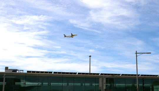 Barcelona-El Prat Josep Tarradellas Airport terminal building with planes on the tarmac and mountains in the background