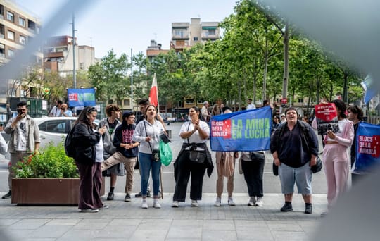 Exterior view of public housing blocks in La Mina, Sant Adrià de Besòs, with residents gathered outside.