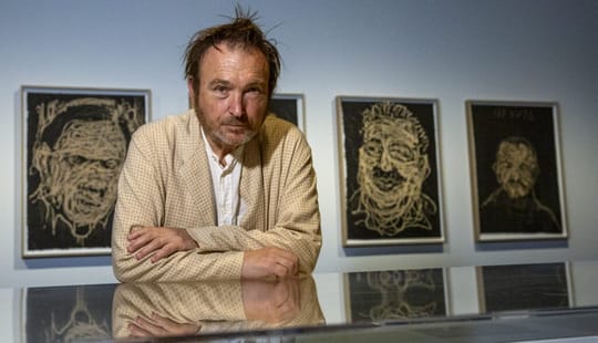 Miquel Barceló standing next to one of his large, textured engravings featuring marine elements, possibly an octopus, in an a