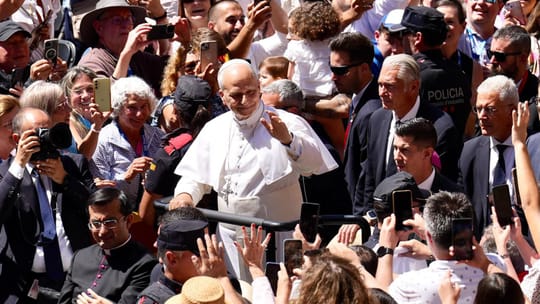 Pope Leo XIV waves from a plane's steps at Barcelona Airport with officials watching his departure.