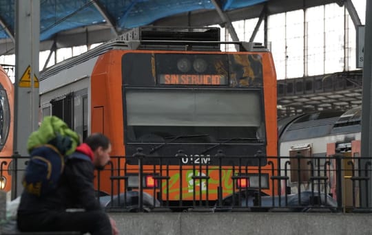 A Rodalies train arriving at a station platform in Barcelona, with passengers waiting to board.