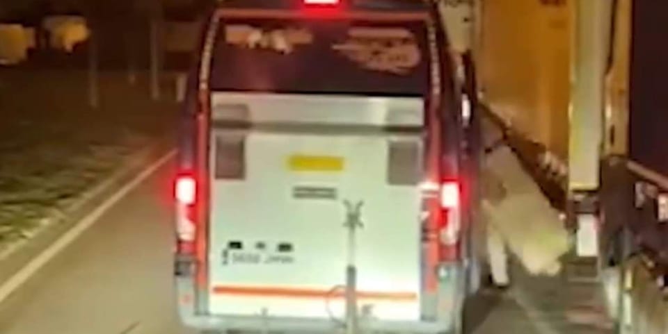 A long-haul truck parked at a service area on the AP-7 motorway at night, with a police patrol car in the background.