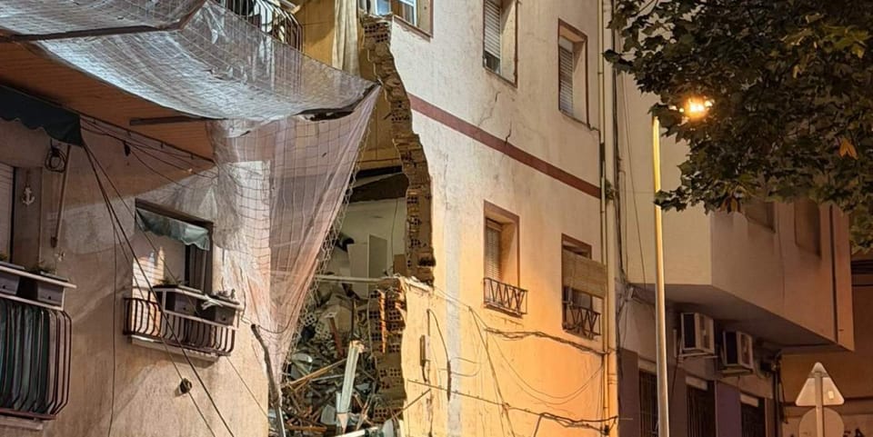 Emergency services at night around a partially collapsed building in Badalona, with debris on the street.