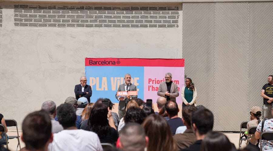 Mayor Jaume Collboni handing keys to a resident in front of a modern apartment building with balconies and a green space.