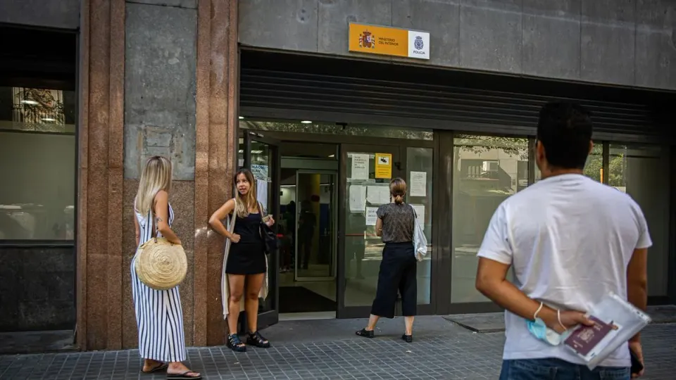 A person holding a smartphone displaying the MiDNI application with a blurred background of a police station interior.