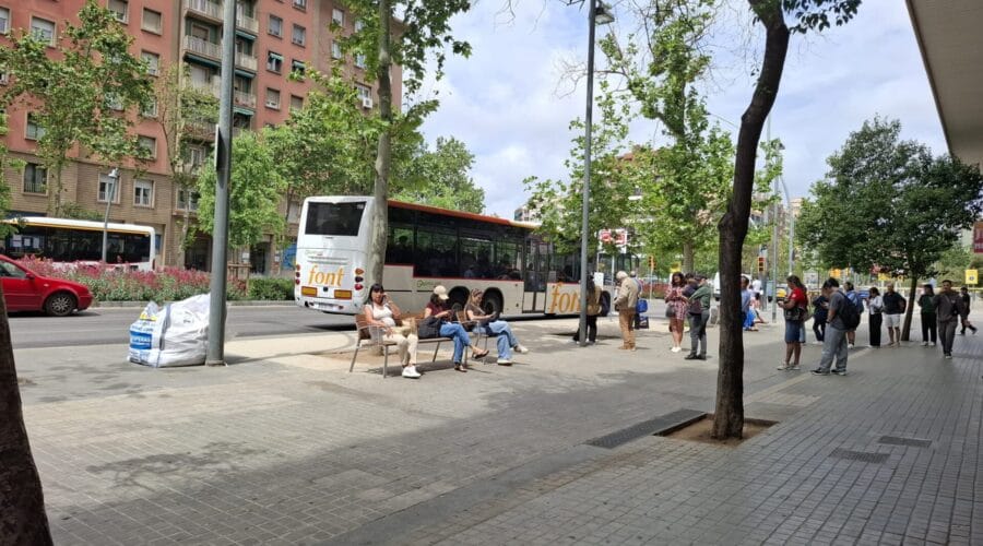 A modern intercity bus stop in Barcelona with a bus arriving, showing new shelters, seating, and clear signage.