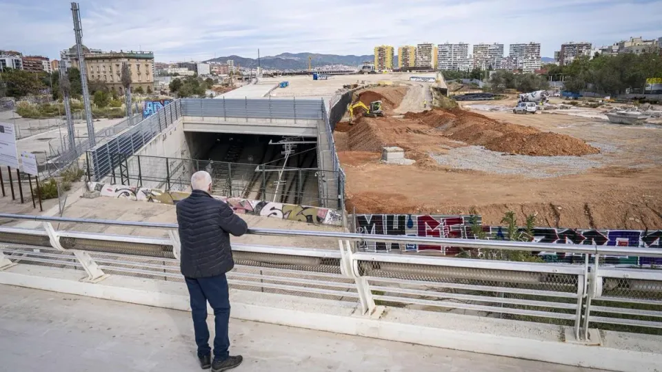 A modern Barcelona Metro train arriving at a station platform, with people waiting to board.