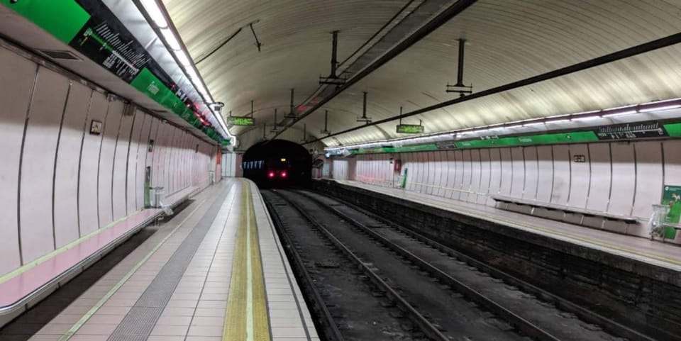 Police officers apprehending a suspect near a metro station entrance in Barcelona.