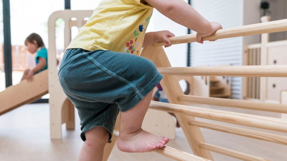 Children playing with blocks and toys in a bright Barcelona nursery school classroom.