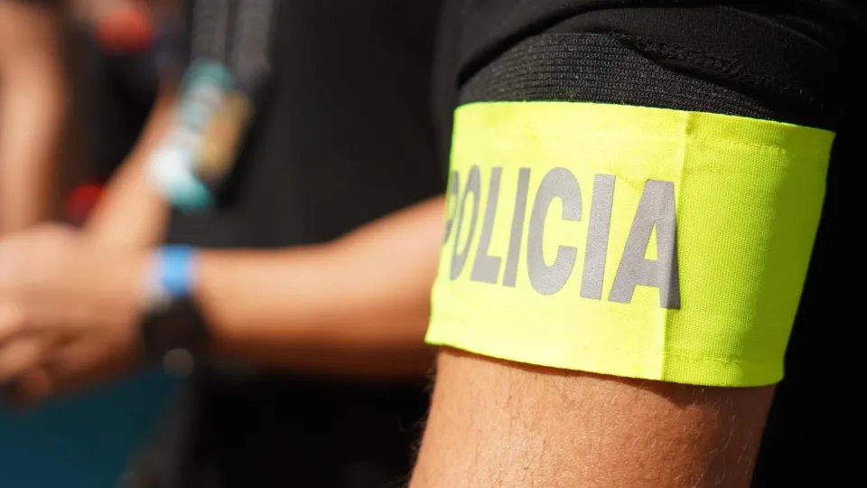 Police officers inspecting a gold-buying shop counter with jewellery displays in Barcelona.
