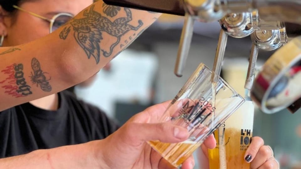 People enjoying food and drink at an outdoor festival with stalls and a lively atmosphere in Barcelona.