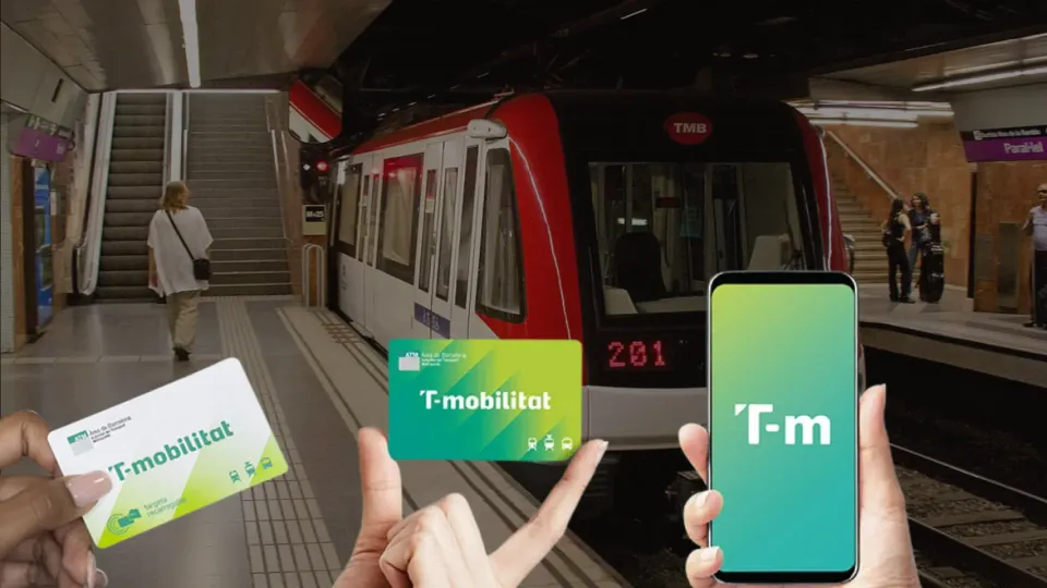 A person holding a T-mobilitat plastic card near a public transport validator in Barcelona.