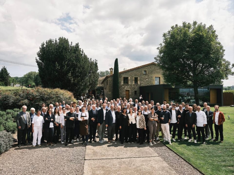 Ferran Adrià embracing a member of the Santamaria family at an event in Tona, surrounded by other chefs.