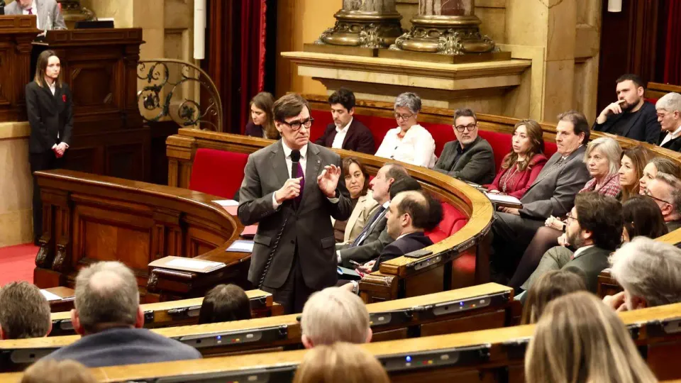 Catalan President Salvador Illa speaking at the Parlament de Catalunya, with deputies in the background.