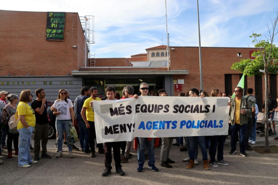 A plainclothes Mossos d'Esquadra officer standing near a school entrance in Catalonia.