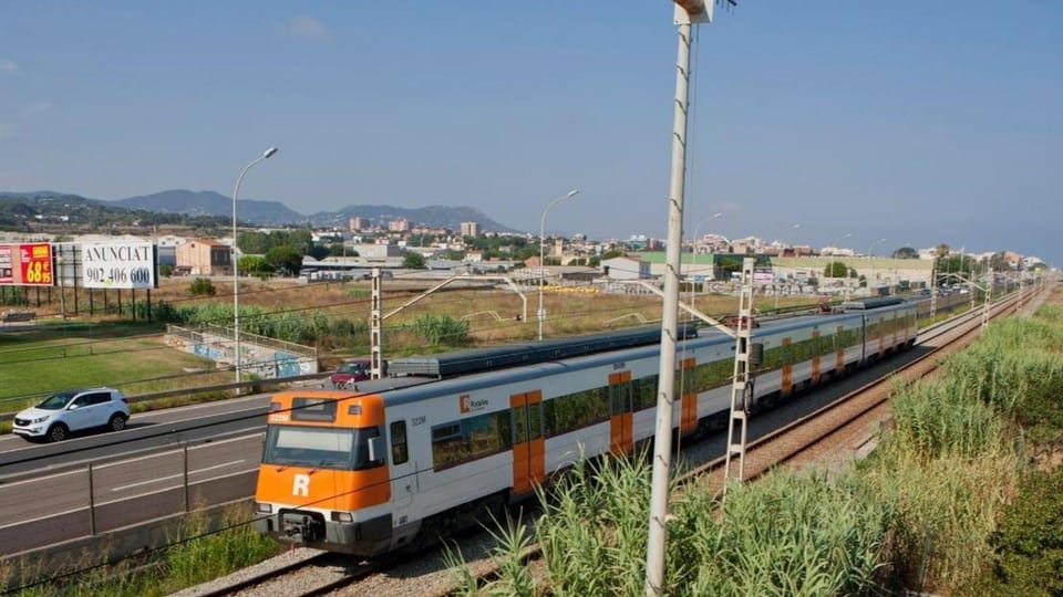 A commuter train on railway tracks near a station, with a city skyline in the background, symbolising urban transport infrast