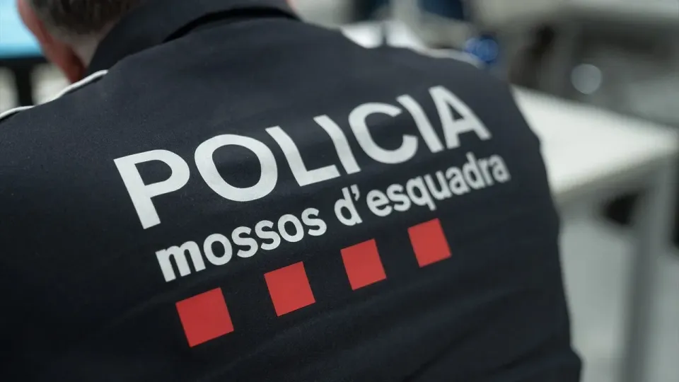 Police car with flashing lights, possibly Mossos d'Esquadra, in a residential area, symbolising a police operation.
