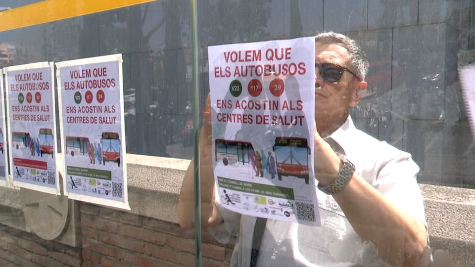 Guinardó residents hold signs during a protest outside Sant Pau Hospital in Barcelona, advocating for improved bus access.