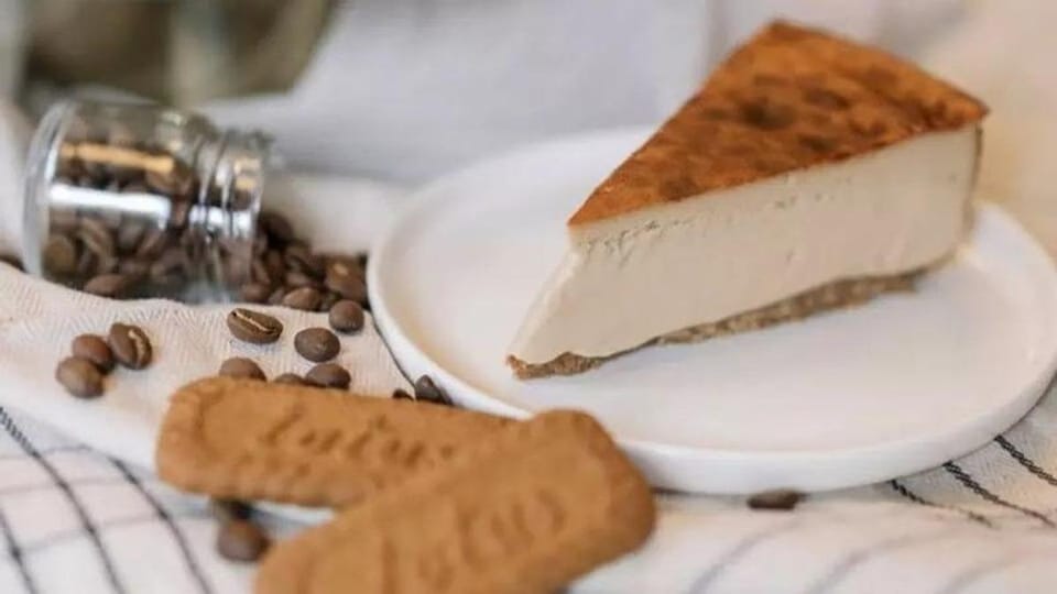 A slice of creamy cheesecake with a slightly burnt top, characteristic of Basque style, on a white plate next to a fork.