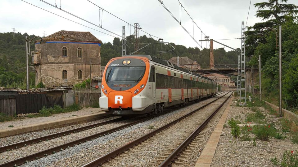 A Rodalies R4 train at a station platform in the Barcelona metropolitan area, with commuters waiting.