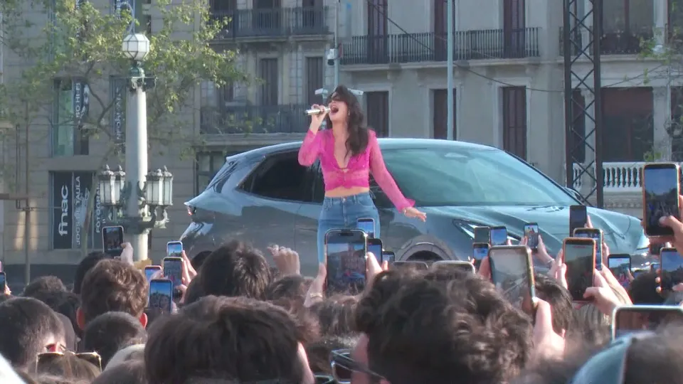 Nathy Peluso performing on stage at a free concert in Barcelona's Plaça de Catalunya, with a large crowd visible.