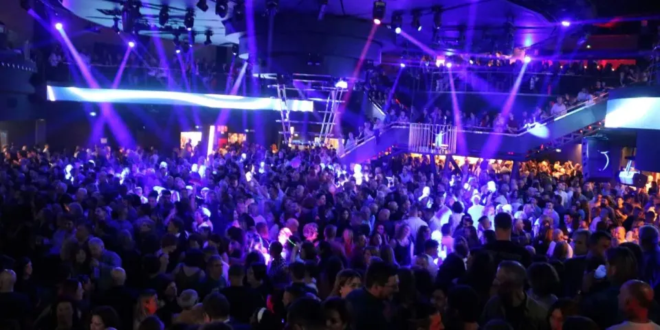 Police officers detaining a suspect outside a nightclub in Barcelona at night.