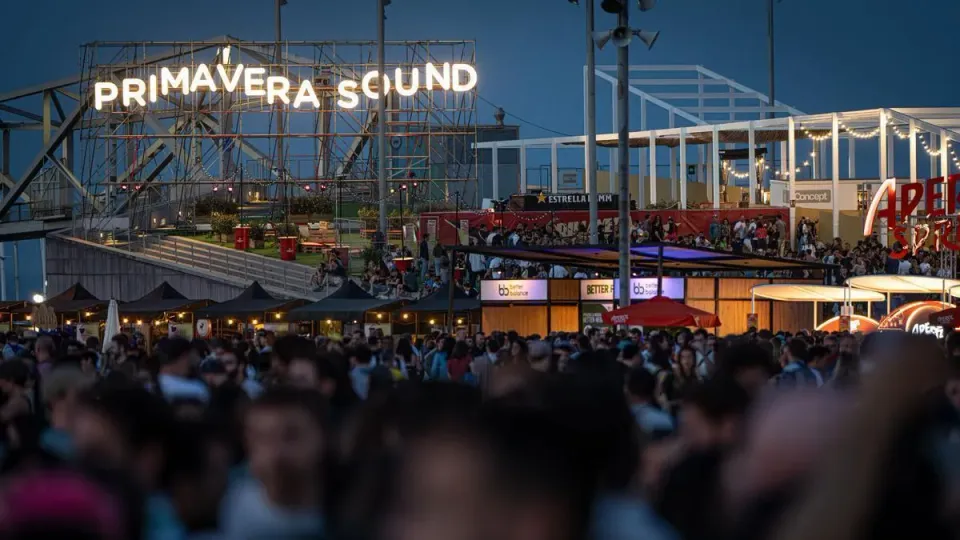 A crowd of people enjoying a music concert at an outdoor festival in Barcelona, with a stage and lights in the background.
