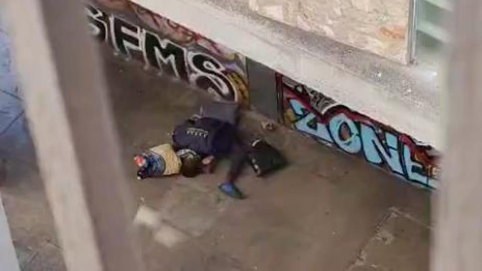 A narrow, dimly lit street in Barcelona's Raval district at night, with some rubbish visible and a sense of unease.