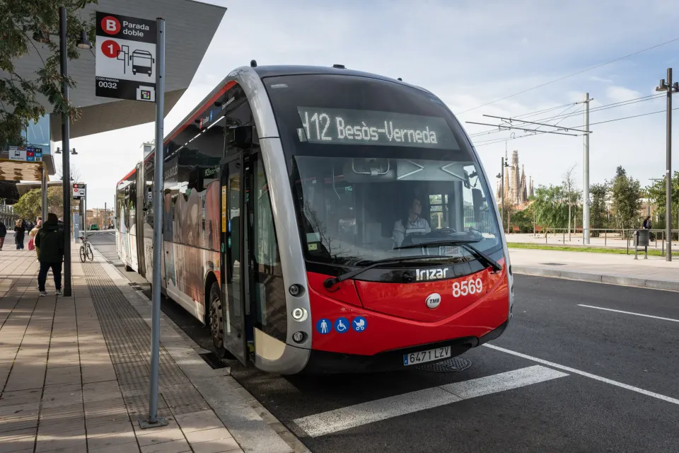 A Barcelona metro train arriving at a station platform with passengers waiting