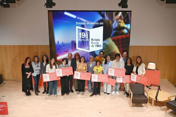 A group of people, including children and adults, stand on a stage receiving awards at a literary event in a library setting.