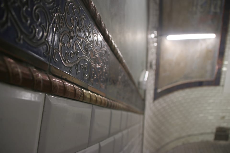 A view of the historic spiral staircase inside Barcelona's Urquinaona Metro station, showing white and blue tiles.