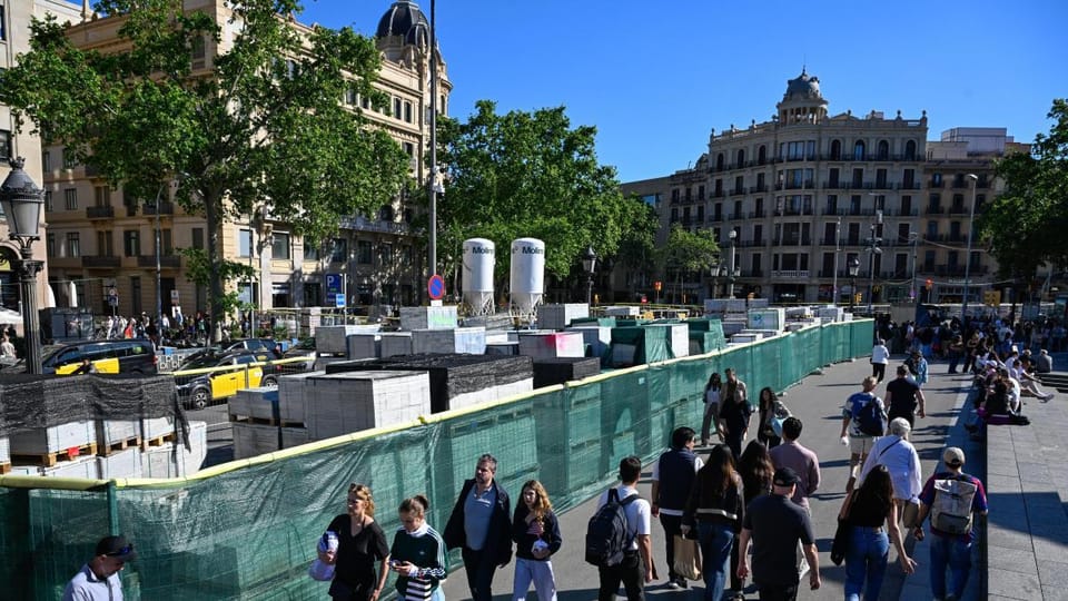 Construction barriers and machinery on a street in Barcelona, with yellow fences and signs indicating ongoing public works.