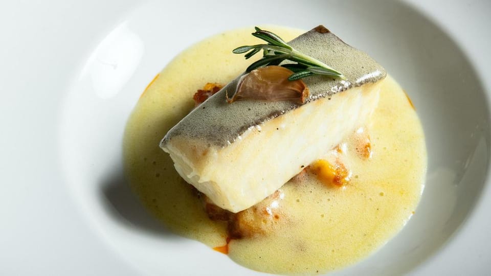 A plate of cod 'a la llauna' with crispy skin and beans, served in a traditional Barcelona restaurant.