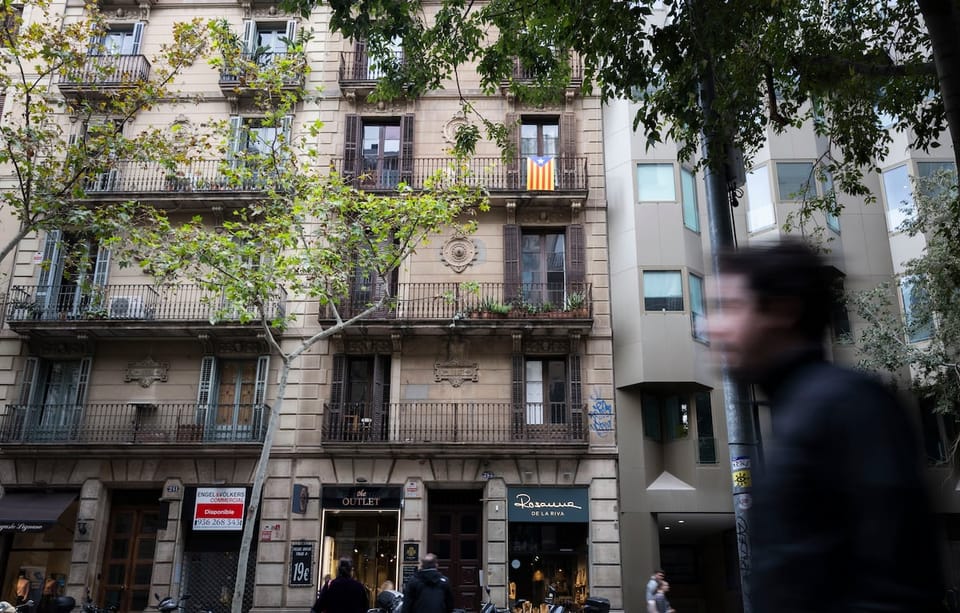A view of multiple residential buildings in Barcelona's Eixample district under a clear sky, showing dense urban housing.