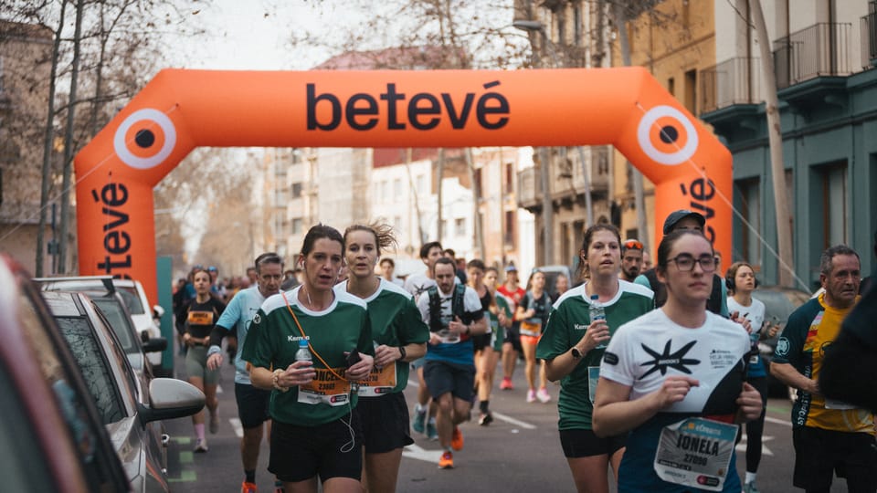 Runners participating in the Barcelona Half Marathon, passing along a wide city street with historic buildings and spectators