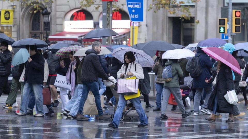 Heavy rain falling over Barcelona city with dark clouds in the sky and wet streets, showing a typical urban scene during a st