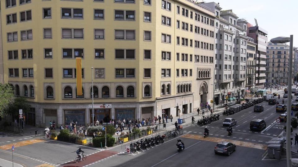 A wide, newly paved pedestrian street in Barcelona with trees and people walking, showing an example of urban pacification.