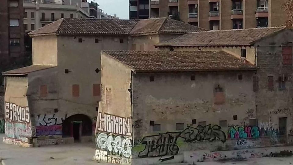 The neglected medieval Torre del Fang building in Barcelona, showing signs of disrepair and overgrowth.