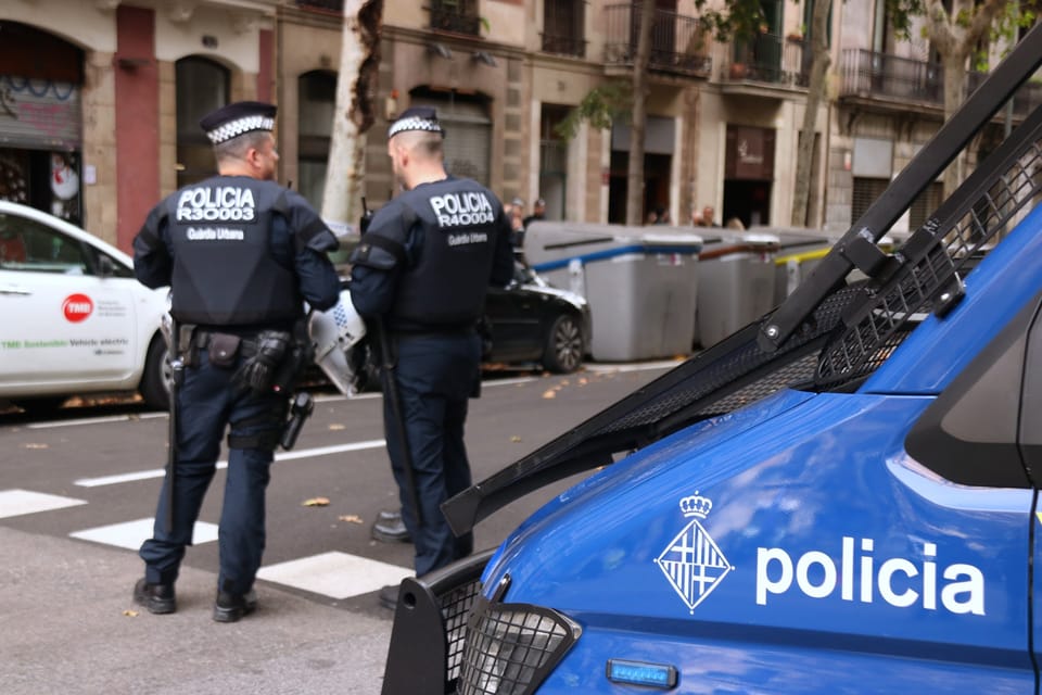 Police vehicles, possibly Guardia Urbana or Mossos d'Esquadra, parked on a street in Barcelona at night during an operation.
