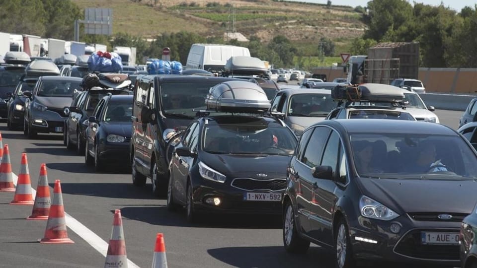 Traffic jam on a multi-lane motorway in Barcelona metropolitan area during a holiday exodus, with many cars visible.