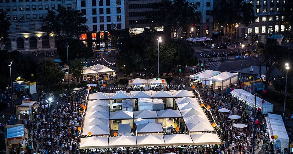 People enjoying small plates of food at an outdoor gastronomic festival in Barcelona's Plaça de Catalunya