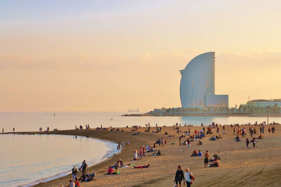 People enjoying Barceloneta Beach in Barcelona with the W Hotel in the background.
