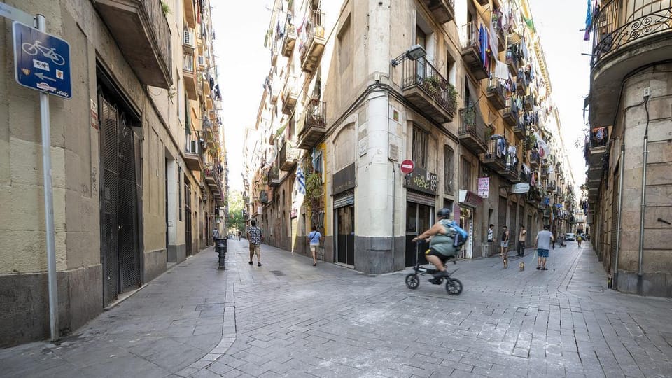 A bustling street scene in Barcelona's Ciutat Vella district, showing historic buildings and pedestrians, symbolising urban r