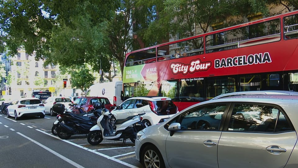 Tourist buses stuck in traffic on a narrow street near Sagrada Familia in Barcelona's Eixample district.
