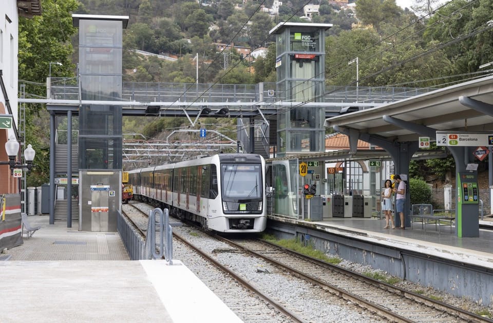 An FGC train arriving at a station platform in Barcelona, with passengers waiting.